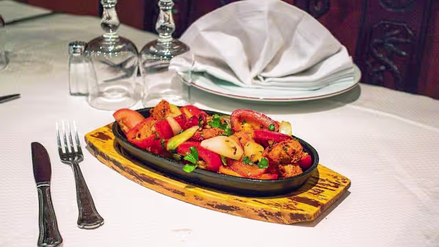 Plat de légumes grillés mélangés et de poulet mariné, garni d'herbes hachées, avec des poivrons rouges, des oignons verts et du poulet doré.