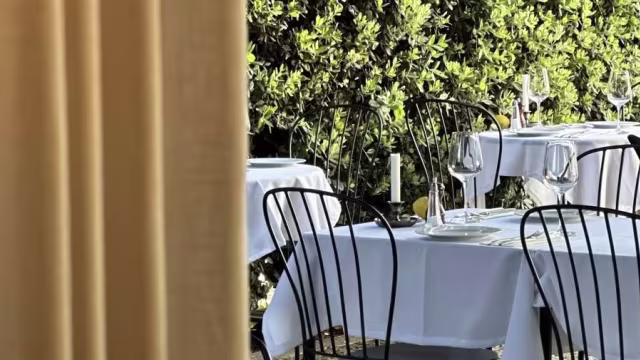 Área de refeições ao ar livre com mesas organizadas e toalhas brancas, rodeadas por vegetação exuberante, criando uma atmosfera natural e serena.
