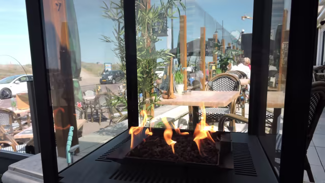 Gezellige restaurantinterieur met modern design, inclusief een stijlvolle open haard en uitzicht op buitenzitplaatsen.