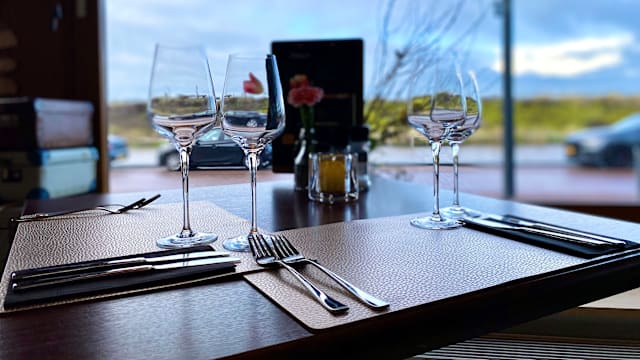 De afbeelding toont een elegant gedekte tafel voor een maaltijd, met verfijnde wijnglazen en een stijlvol middelpunt van verse bloemen, wat bijdraagt aan een uitnodigende sfeer voor een ontspannen diner.