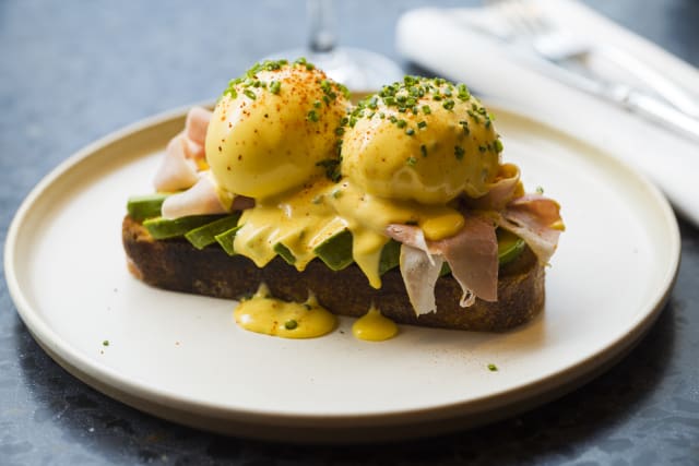 Huevo benedict con bacon | Huevo a baja temperatura, bacon, aguacate en láminas, queso gruyère y salsa holandesa de azafrán sobre pan de masa madre