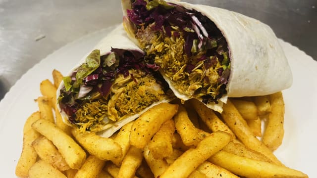 Hearty wrap filled with seasoned shredded chicken, crisp lettuce, and purple cabbage, accompanied by golden, crispy French fries.