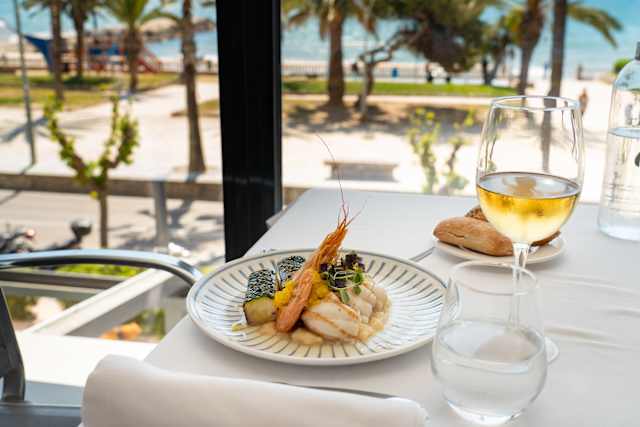 Plato de mariscos con camarón grande, pescado blanco y sushi, adornado con microgreens.
