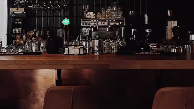 Stijlvolle bar met een gepolijst houten aanrecht, een moderne uitstraling, en een zorgvuldig geselecteerde drankjes in een gezellige sfeer.