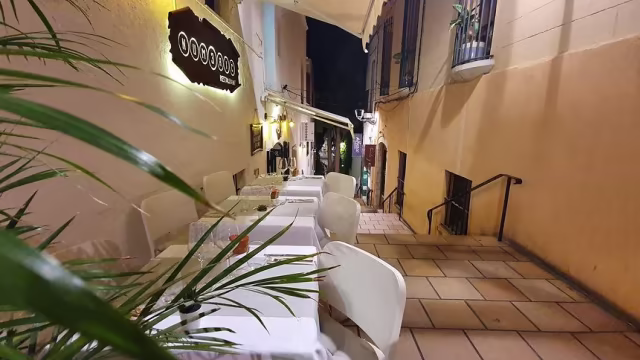 Área de comedor al aire libre con mesas elegantes y un ambiente acogedor, ideal para disfrutar de una comida al fresco.