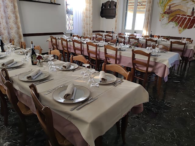 Interno di un ristorante spazioso con tavoli ben disposti, tovaglie chiare e decorazioni murali, che creano un'atmosfera accogliente.