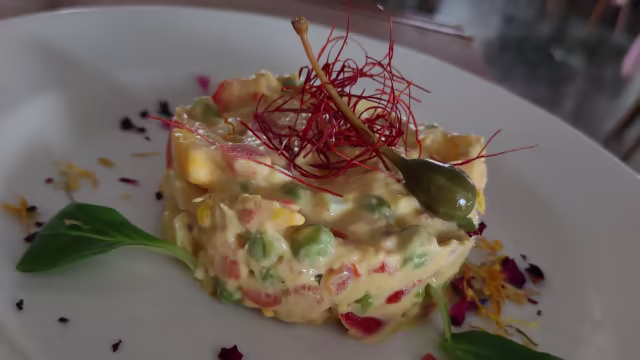 Misto cremoso di verdure tritate, pomodori e peperoni, guarnito con zafferano, cappero e fiori edibili.