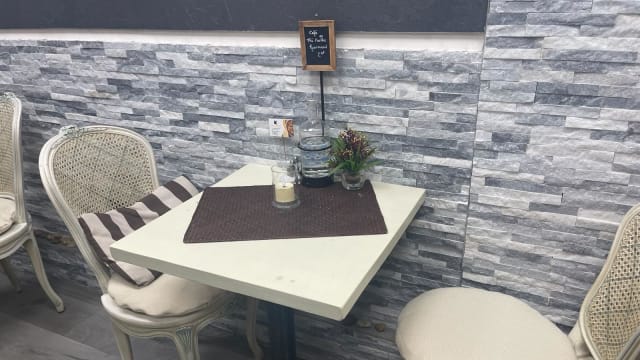 Table d'un restaurant cosy avec une ambiance chaleureuse, ornée d'un chemin de table sombre et d'une plante en pot.