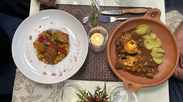 Deux plats distincts : à gauche, des pâtes avec des morceaux de viande braisée dans une sauce riche, garnies de poivron rouge et d'herbes fraîches ; à droite, un plat en terre cuite avec de la viande mijotée, recouverte de fromage fondu, accompagnée de tranches de pommes de terre vertes.