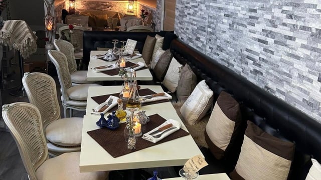 Intérieur de restaurant chaleureux avec des tables bien disposées, nappes blanches, bougies décoratives, et sièges confortables aux tons neutres, le tout sous un éclairage doux.