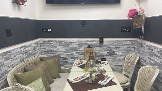 Intérieur de restaurant chaleureux avec des murs en pierre texturée et des accents sombres, créant une ambiance accueillante pour une expérience de repas intime.