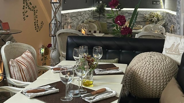 Intérieur de restaurant chaleureux et moderne, avec un éclairage doux, des plantes décoratives et des sièges confortables, créant une ambiance accueillante pour un repas.