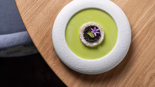 Mousse ou pâté crémeux surmonté de caviar noir, accompagné d'une sauce verte lisse à base de légumes et décoré d'une fleur comestible.
