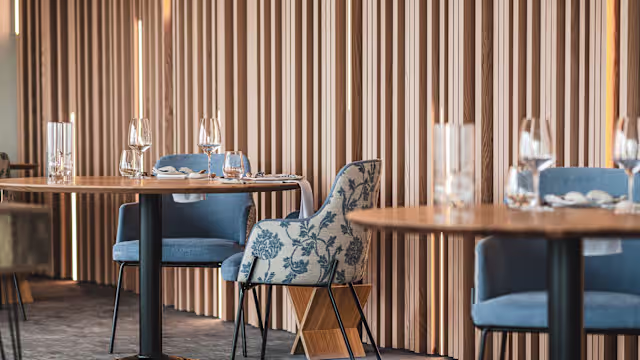 Intérieur de restaurant moderne avec des panneaux en bois, créant une atmosphère chaleureuse et accueillante, des tables élégamment dressées et un éclairage doux.