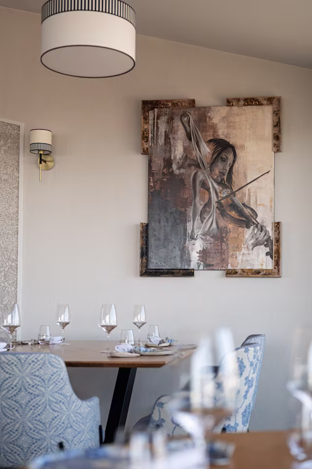 Intérieur de restaurant élégant avec un design moderne, des œuvres d'art raffinées aux murs, un éclairage doux et des tables soigneusement dressées.