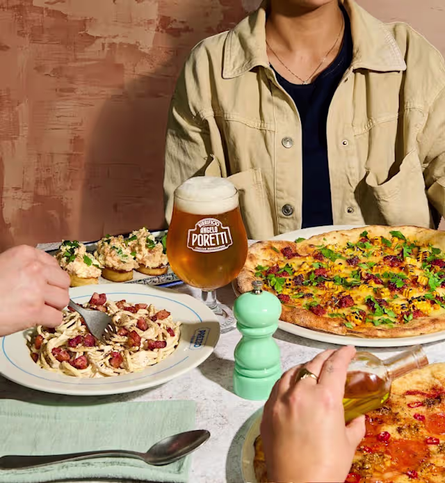 Creamy pasta with bacon and herbs, colorful pizza with bell peppers and onions, and bruschetta topped with fresh herbs and tomatoes, complemented by a beer labeled 'POKETT.'