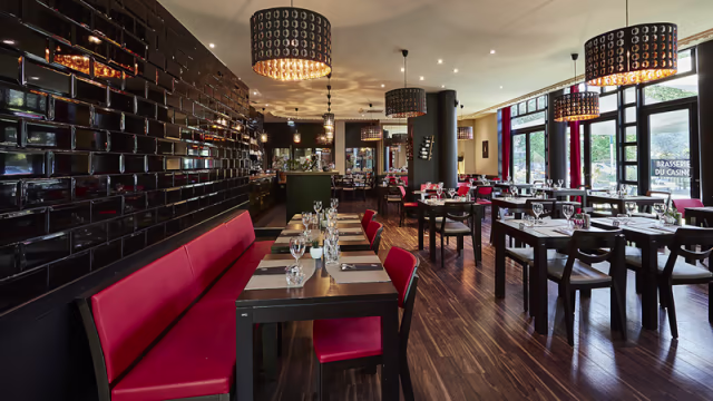 Intérieur moderne avec des murs noirs et des bancs en velours rouge, créant une ambiance contemporaine et accueillante.