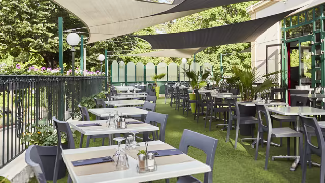 Espace de restauration en plein air avec des tables bien disposées sur une pelouse verte, ombragé par de grandes toiles, offrant une ambiance agréable et relaxante.