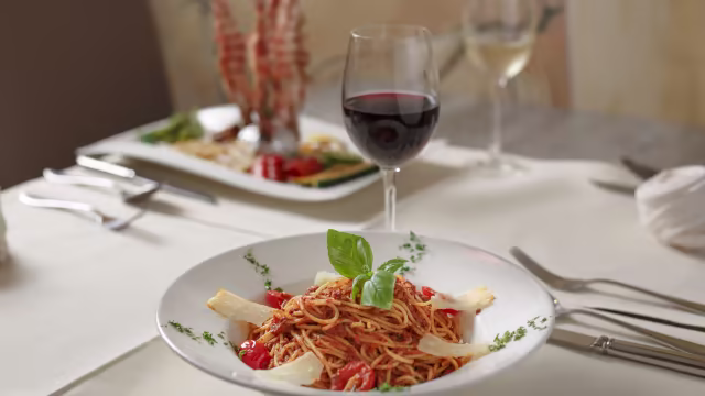 Spaghetti met rijke tomatensaus, verse basilicum en stukjes rijpe tomaat, geserveerd met gesmolten witte kaas.