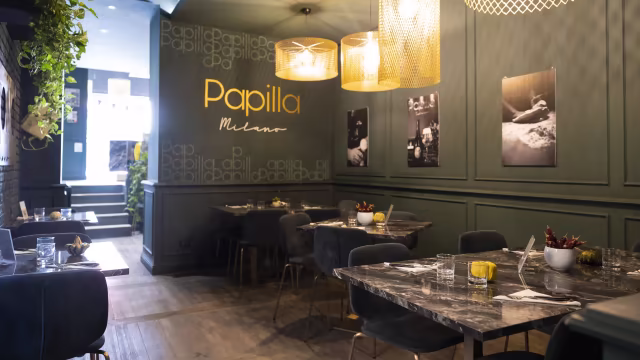 Interni moderni ed eleganti con pareti verde scuro, fotografie stilose e illuminazione calda.