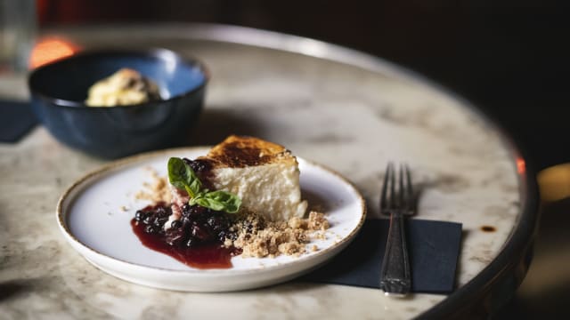 Cheesecake con crumble de almendra y coco, salsa de frutos del bosque.