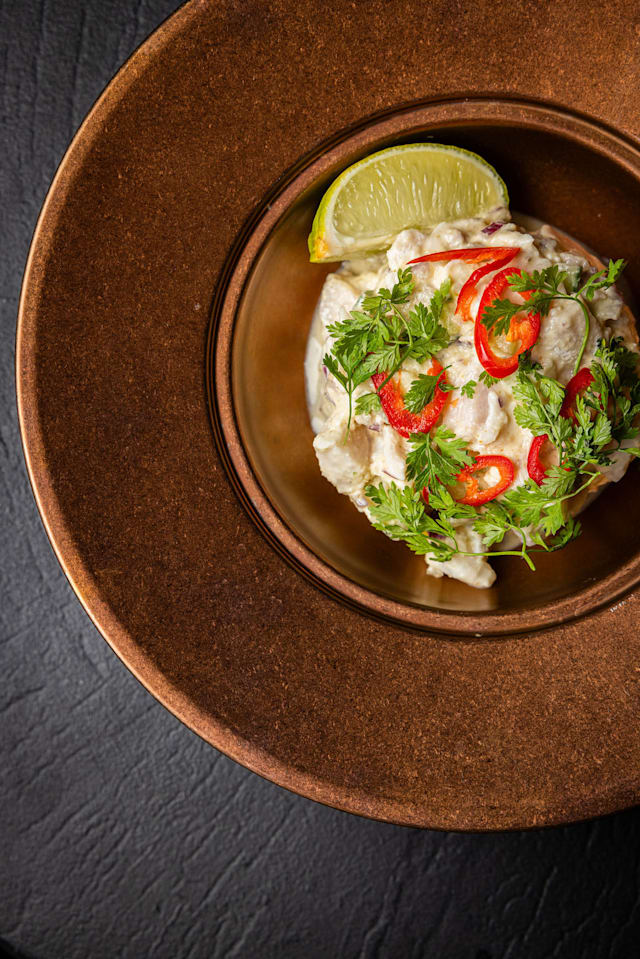 CEVICHE TRADITIONNEL - PÉROU  Daurade crue fraîchement découpée, marinée dans un éclat cosmique de citron vert, coriandre et relevée d'un piment rouge pour une fraîcheur lunaire. Accompagnement au choix.