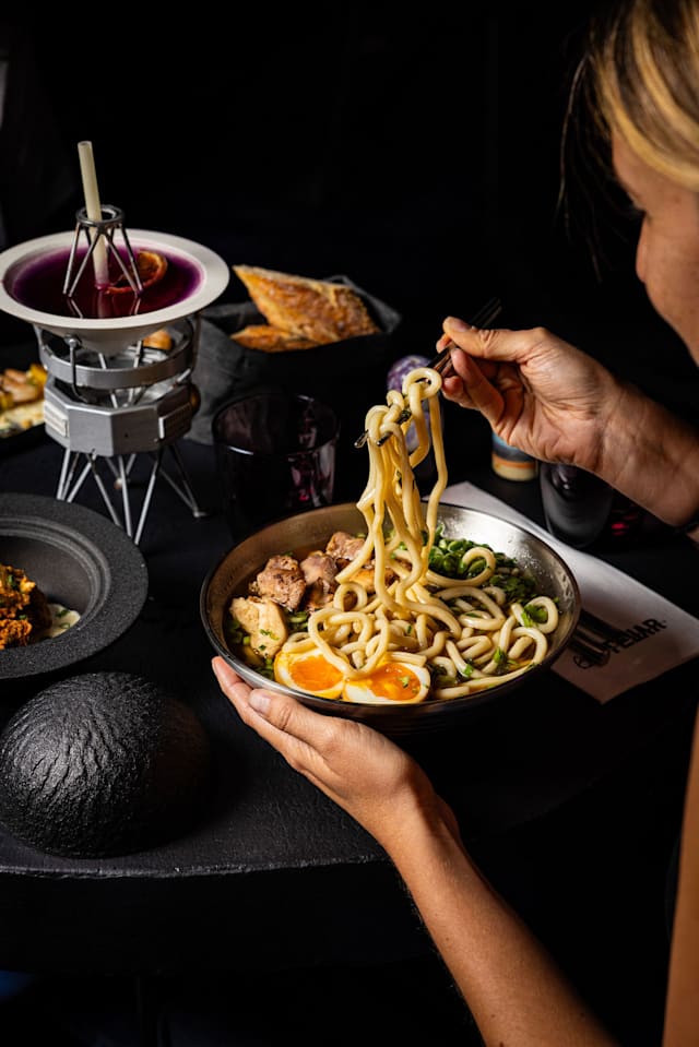 COSMIC RAMEN - JAPON Nouilles udon typiquement japonaises dans un bouillon de poulet maison très aromatique. Accompagnées de légumes frais - daikon croquant et cébettes -, d'un oeuf tamago coulant et de poulet mariné au gingembre et miso. Un bol aux saveurs gravitationnelles qui vous emmène en voyage gustatif.