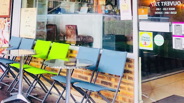 Espace extérieur d'un restaurant avec des chaises pliantes modernes de couleurs vives et des tables rondes pour un repas décontracté, créant une atmosphère relaxante.