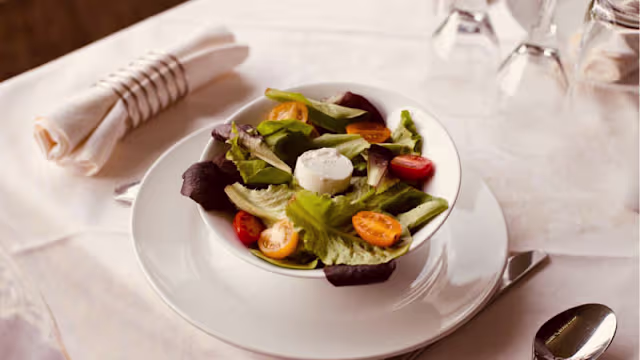 Salade fraîche composée de mélanges de feuilles vertes, tomates cerises colorées et fromage de chèvre crémeux.
