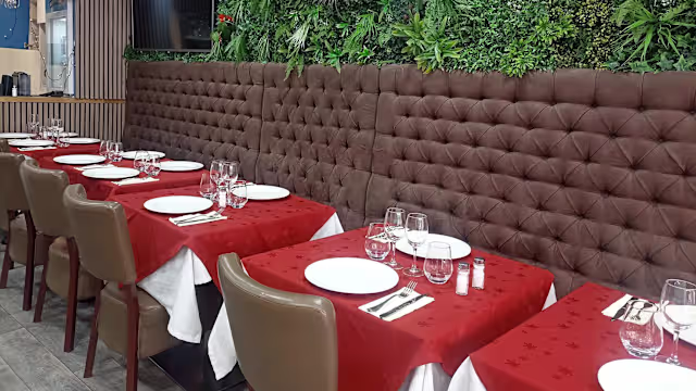 Intérieur de restaurant élégant avec des tables bien disposées, nappes rouges et vaisselle blanche, offrant une ambiance formelle et chaleureuse.
