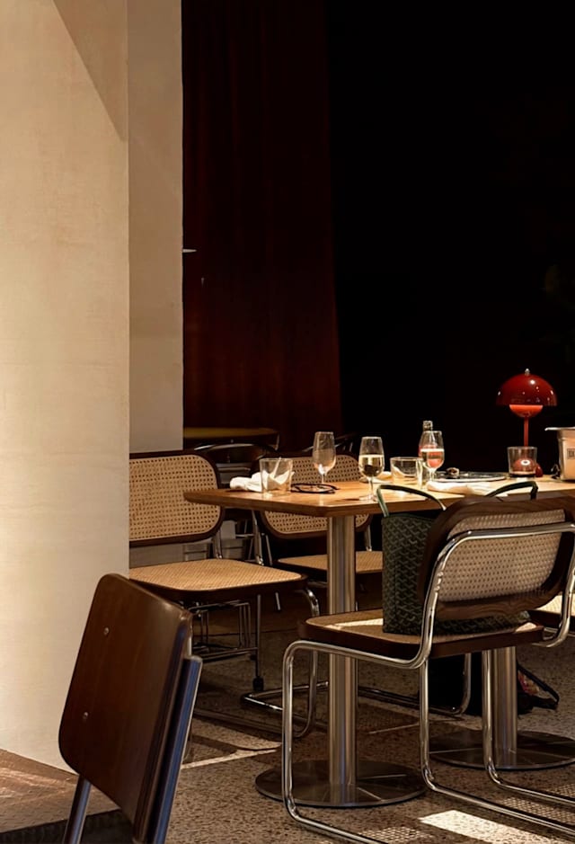 Interni di un ristorante moderno con design minimalista, illuminato da luci soffuse e decorato con colori ricchi.