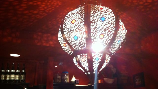 Suspension décorative avec un motif délicat projetant des ombres complexes, créant une ambiance chaleureuse et accueillante, idéale pour un repas.