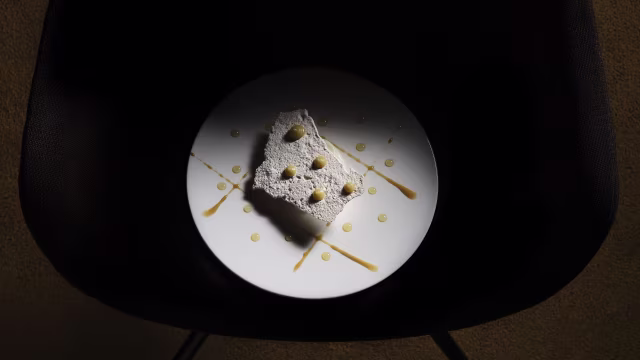 Dessert raffinato a base di torta leggera o mousse, guarnito con salsa cremosa e noci croccanti.