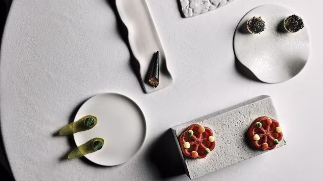 Piccole paste rotonde con glassa di frutta e crema, accompagnate da verdure verdi ripiene di una miscela cremosa, e dessert al cioccolato in un'presentazione minimalista.
