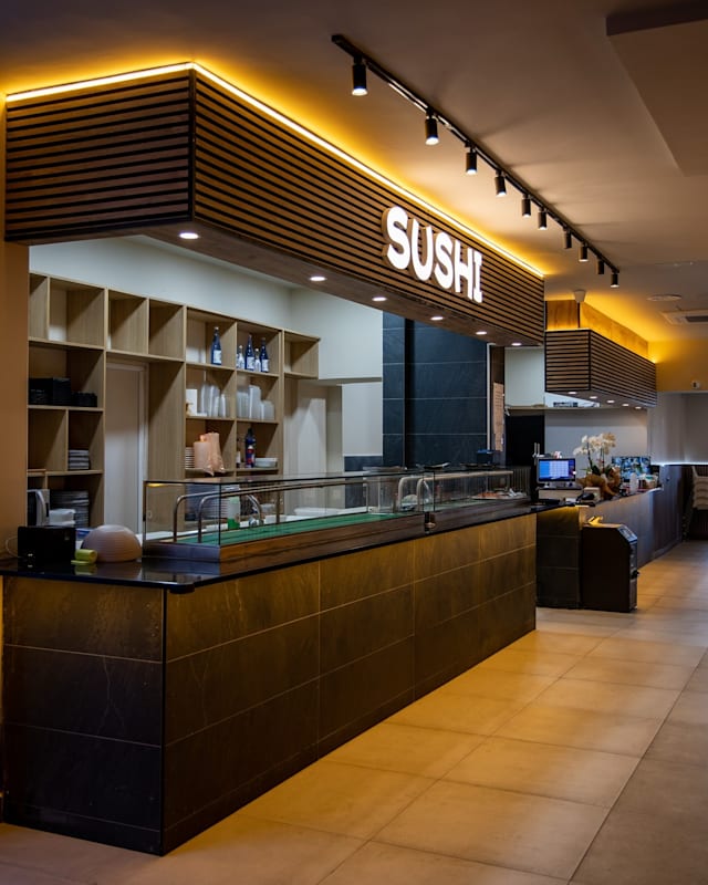 Restaurante de sushi moderno con un diseño minimalista, mostrador de piedra oscura y iluminación cálida.