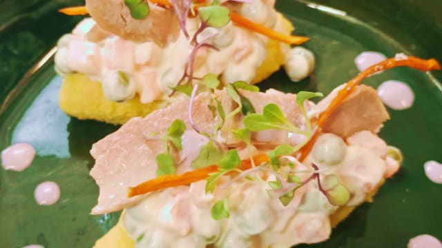 CAUSA LIMEÑA: Patata andina amasada con ajíes, topping de verduras, ventresca de atún, mayonesa y salsa de aceituna peruana de botija. Es un platillo con historia, la de un país con más de 3,500 variedades de patatas o papas 🥔. Su origen pudo ser inca, su nombre puede provenir del vocablo quechua Kausaq, nombre que le daban a la papa y cuyo significado era “sustento de vida”. Otras teorías, se remontan al siglo XIX, a las luchas por la independencia del Perú y otras a la Guerra del Pacífico, en ambos casos a fin de apoyar a los soldados peruanos, las mujeres se organizaron para recaudar insumos, emplearlos para preparar platillos que luego eran vendidos. Esa ganancia era invertida en la compra de medicinas, ropa y alimento para los hombres de guerra. La papa fue el insumo más utilizado; hervida, prensada y sazonada con un poco de sal y ají amarillo, era vendida en las plazas bajo el lema: “Por la causa” o “Por la causa limeña”, en referencia a la lucha que se llevaba a cabo en ese momento. Cualquiera que sea su origen, la Causa es uno de nuestros platos bandera, es único y de los más característicos de la cocina peruana. ❤️🤍❤️