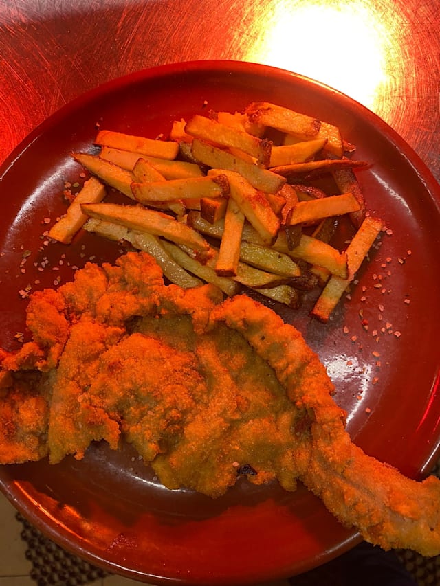 Pescado frito dorado con papas fritas crujientes.