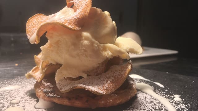 Piatto di gelato cremoso con patatine croccanti, spolverato di zucchero a velo e guarnito con salsa cremosa.