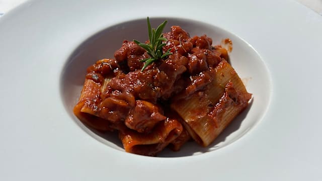 Pacchero alla genovese di polpo cotto nel Morellino di Scansano Un piatto ricco di gusto e originalità: paccheri conditi con una genovese di polpo, dove la sapidità del mare incontra la profondità del Morellino di Scansano. Il polpo viene cotto lentamente nel vino rosso, che ne esalta la morbidezza e dona al sugo un carattere deciso e avvolgente. Un primo che conquista con ogni forchettata.