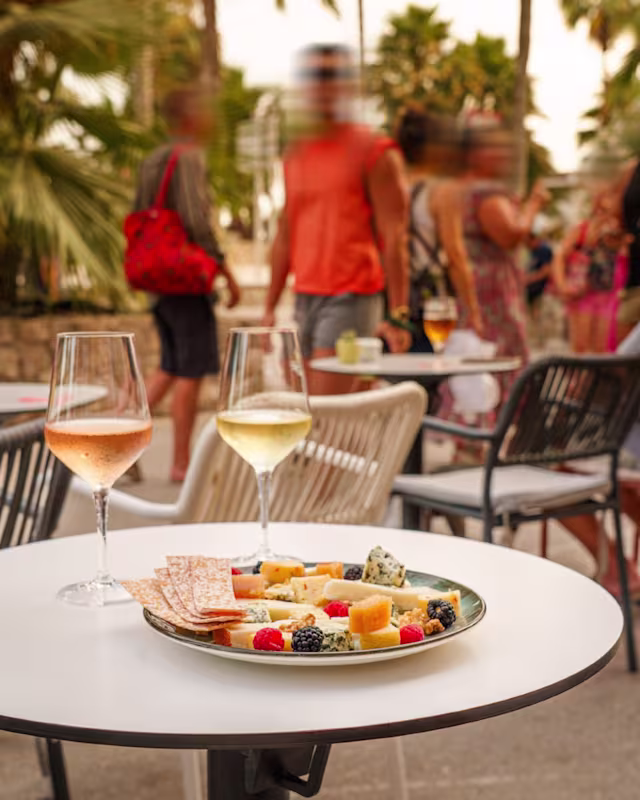 Plato de quesos variados, suaves y duros, acompañado de frutas frescas y bayas, en un ambiente al aire libre relajado.