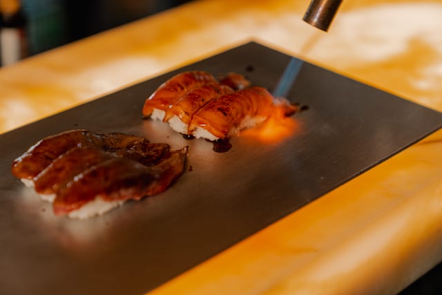 Een gerecht wordt vakkundig met een brander afgewerkt, een culinaire beleving bij Azura.