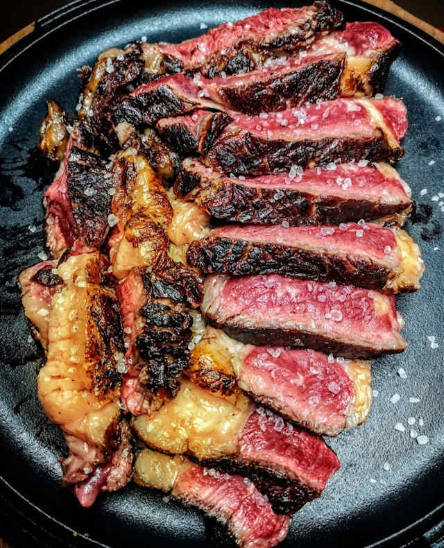 Plato de carne asada a la parrilla con cortes variados, jugosa y tierna, realzada con sal gruesa.