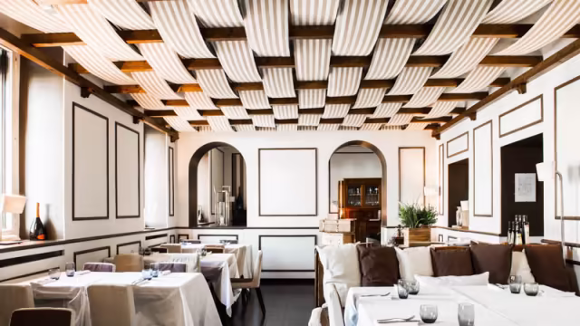 Interni moderni ed eleganti con un design minimalista, atmosfera calda e sofisticata adatta a esperienze gastronomiche raffinate.