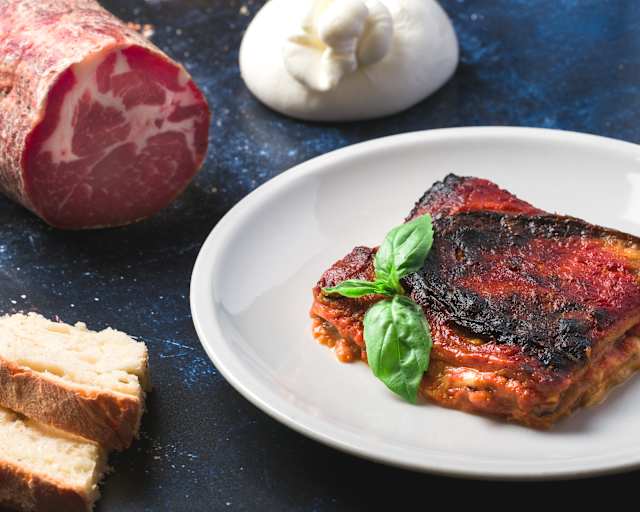 Lasagna a strati con salsa di pomodoro ricca e carne, formaggio fuso e basilico fresco, con bordi croccanti.