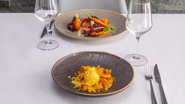 Plato de carne a la parrilla con verduras asadas y risotto cremoso con calabaza y queso.