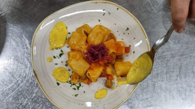Paccheri con crema di pomodoro giallo, salsiccia e cipolla rossa caramellata