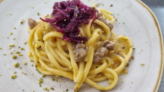 Tagliolini con crema di pomodoro giallo, salsiccia, cipolla rossa caramellata e granella di pistacchio