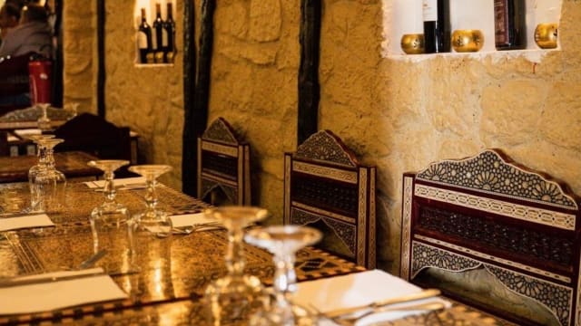 Intérieur de restaurant chaleureux et accueillant avec des chaises en bois sculptées, des tables au fini poli et un éclairage doux, créant une ambiance rustique et élégante.