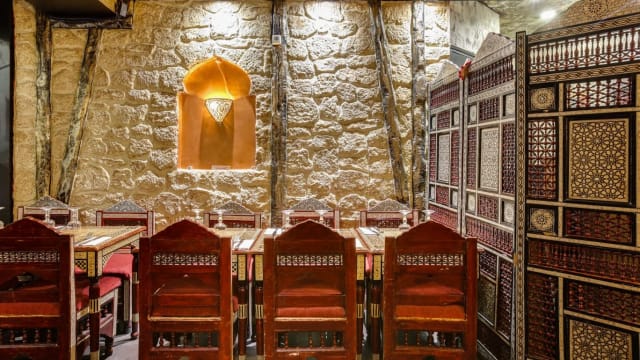 Intérieur chaleureux avec des murs en pierre, tables en bois et chaises artisanales, créant une ambiance conviviale et intime.