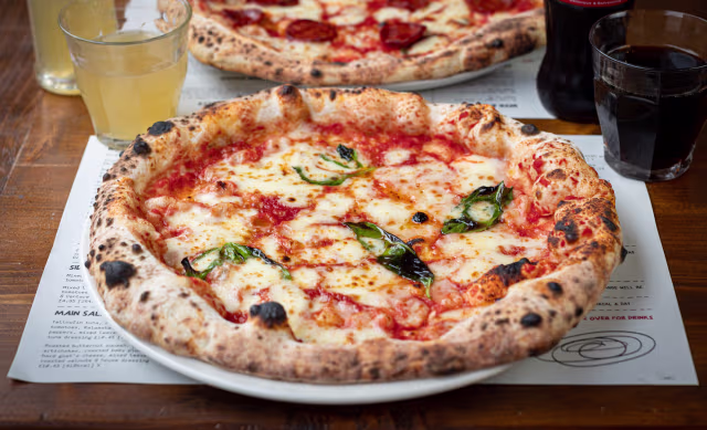 Classic pizza with a golden, chargrilled crust, topped with rich tomato sauce, melted mozzarella cheese, and fresh basil leaves.